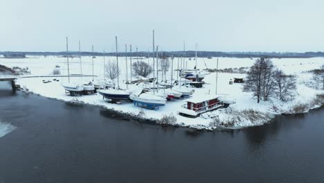 aerial view in winter, the yachts stand on the shore and are covered with a thick layer of snow