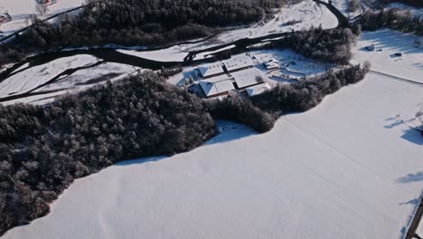 snow-covered landscape with a river, forest, and buildings in giffre, viewed from above