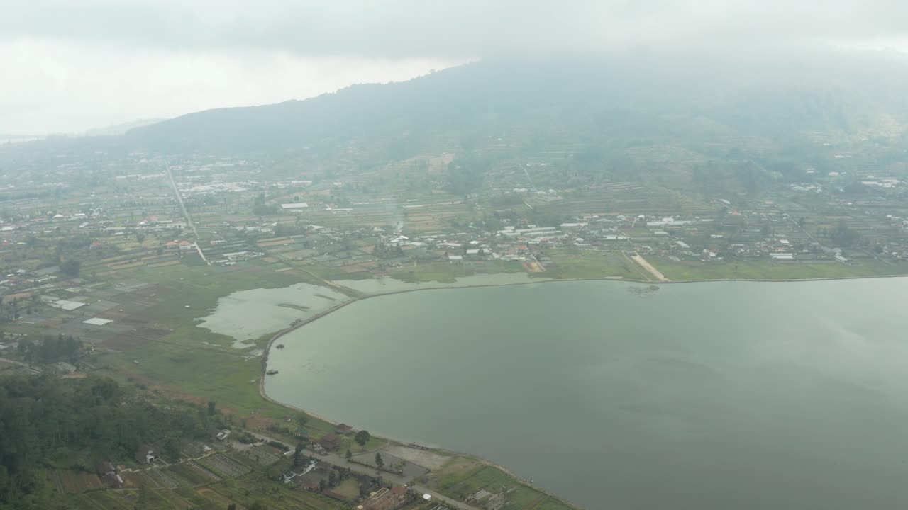 Aerial video; A slow pan overlooking a stunning tropical city residing on the side of a lake
