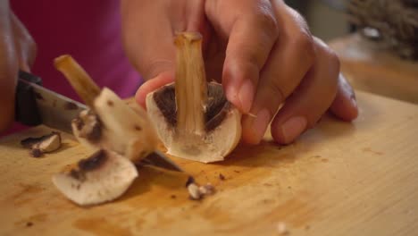 hands slicing mushrooms on a cutting board