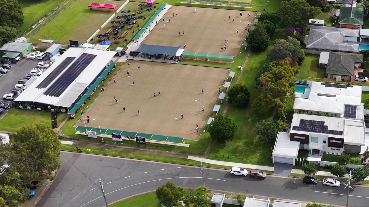 Toma aérea de dron en picado que recorre una instalación deportiva y las casas suburbanas y vegetación circundantes.
