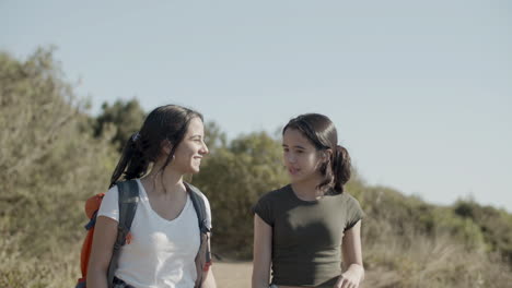 front view of two young girls walking along dirt road, enjoying hiking adventure