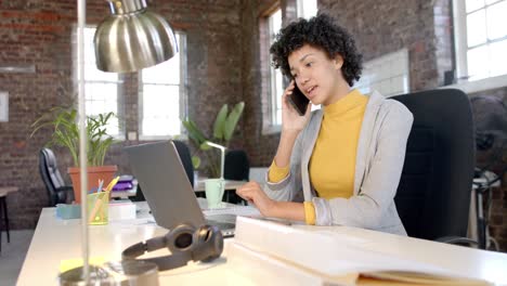 Happy-biracial-casual-businesswoman-talking-on-smartphone-in-office-in-slow-motion