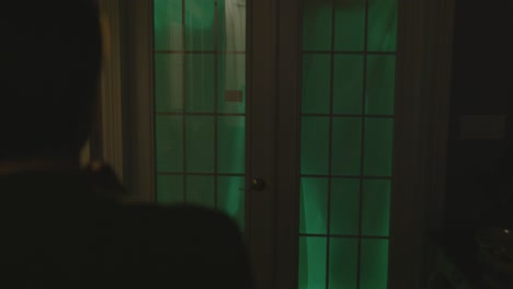 a woman is seen walking to a door where figures are glowing and moving