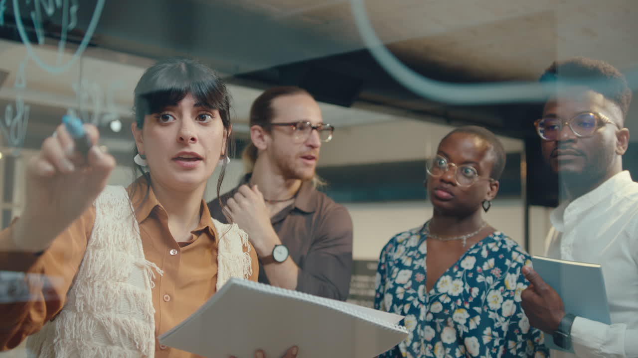 Woman Writing on Glass Wall and Having Discussion with Business Team