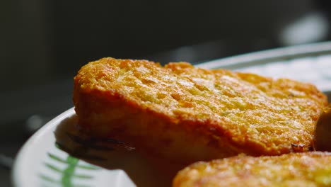 hot cooked crispy hash brown on plate in bright sunlight. potato based food served at breakfast.