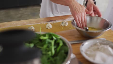 cocinera caucásica enseñando a un grupo diverso preparando platos y sonriendo
