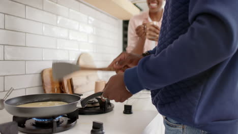 cooking together, african american couple enjoying time in kitchen with frying pan on stove