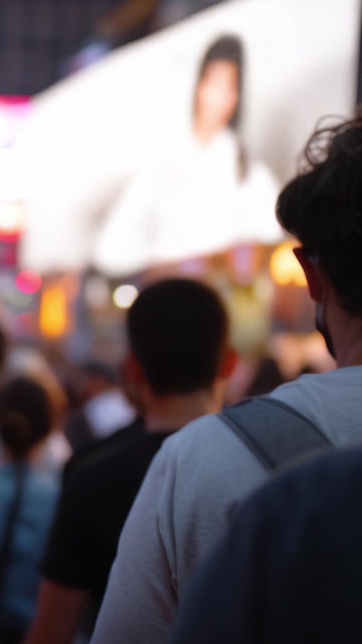 Crowds Gather in a Vibrant City Scene Featuring Colorful Billboards, Illuminated Displays, and Focused Individuals in an Urban Environment