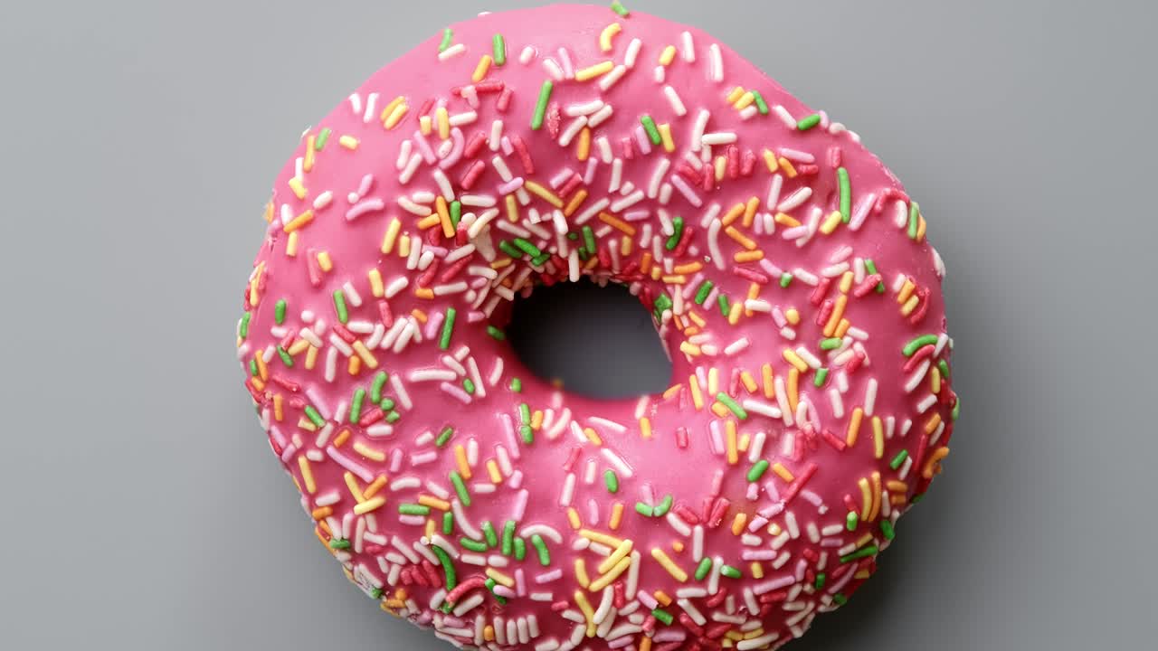 vista superior girando lentamente rosquilla dulce fresca para la pausa para el café o el desayuno aislado en gris