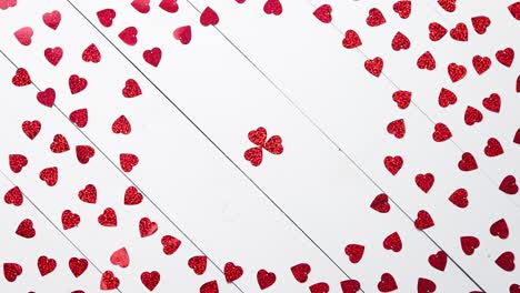 Vlentine\'s-Day-composition--Heart-shaped-sequins-placed-on-white-wooden-table