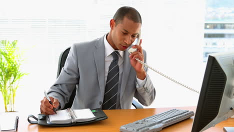 businessman working at his desk and writing in diary