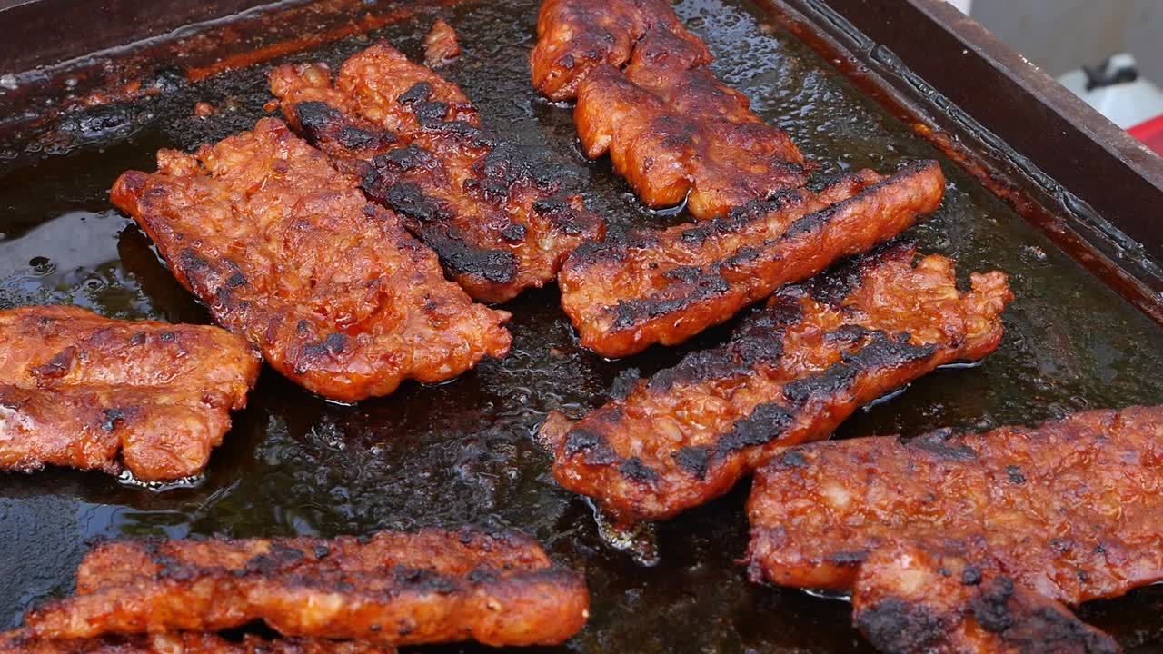 Sliced chorizo and blood sausage slowly cooking on a hot griddle or grill with sizzling fat. Traditional Spanish food, tapas, and Mediterranean cuisine