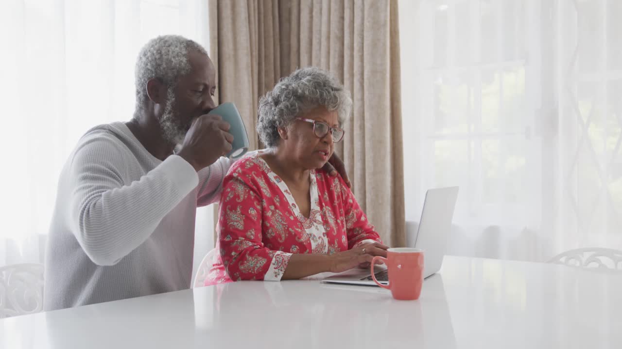 A senior African american couple spending time together working on a laptop in social distancing