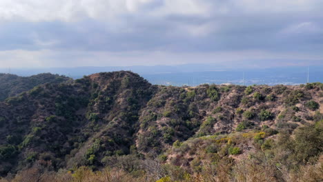 Colinas-Y-Plantas-Rocosas-De-California-Y-Una-Línea-Eléctrica-Frente-A-Una-Ciudad-Distante