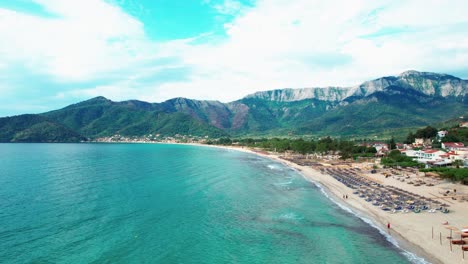 Aerial-Cinematic-View-Of-Golden-Beach-With-Towering-Mountain-Peaks,-Beautiful-Beachfront-And-Lush-Vegetation,-Vivid-Colors,-Thassos-Island,-Greece,-Europe