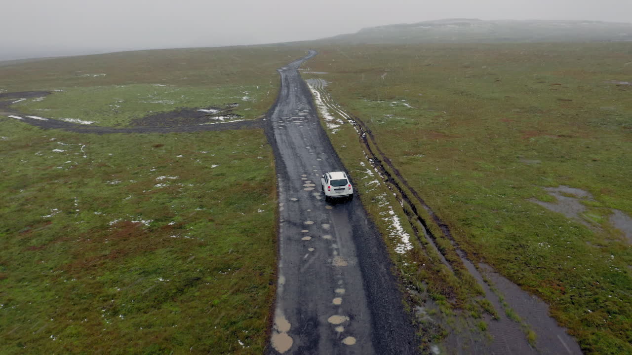 antena: siguiendo un coche blanco en un camino de tierra embarrado mientras nieva