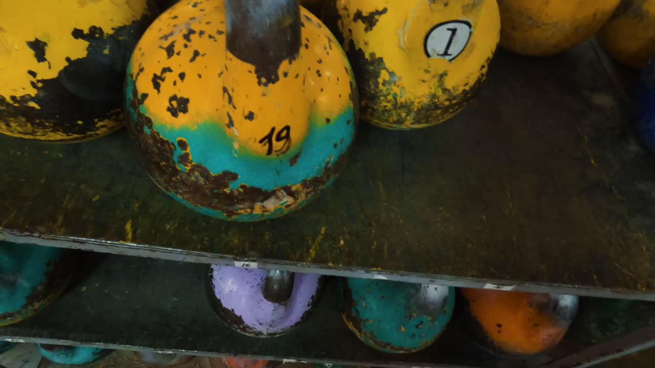 Kettlebells in a gym, with a person's hands reaching for them