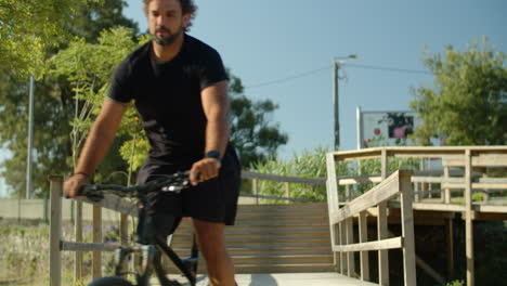 vista frontal de un hombre enfocado con pierna biónica montando una bicicleta en un parque