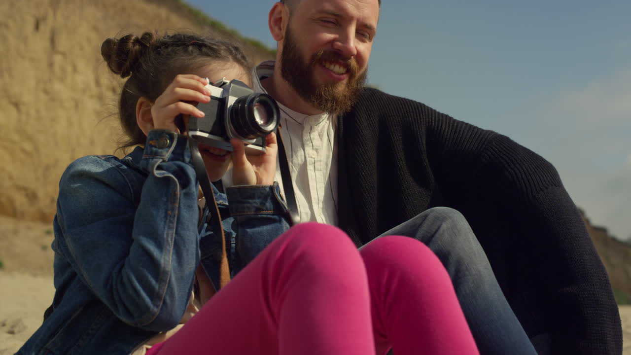 niño tomando fotos en un viaje familiar a la playa. niña linda sosteniendo la cámara afuera.