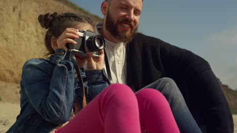 little kid taking pictures on family beach trip. cute girl hold camera outside.