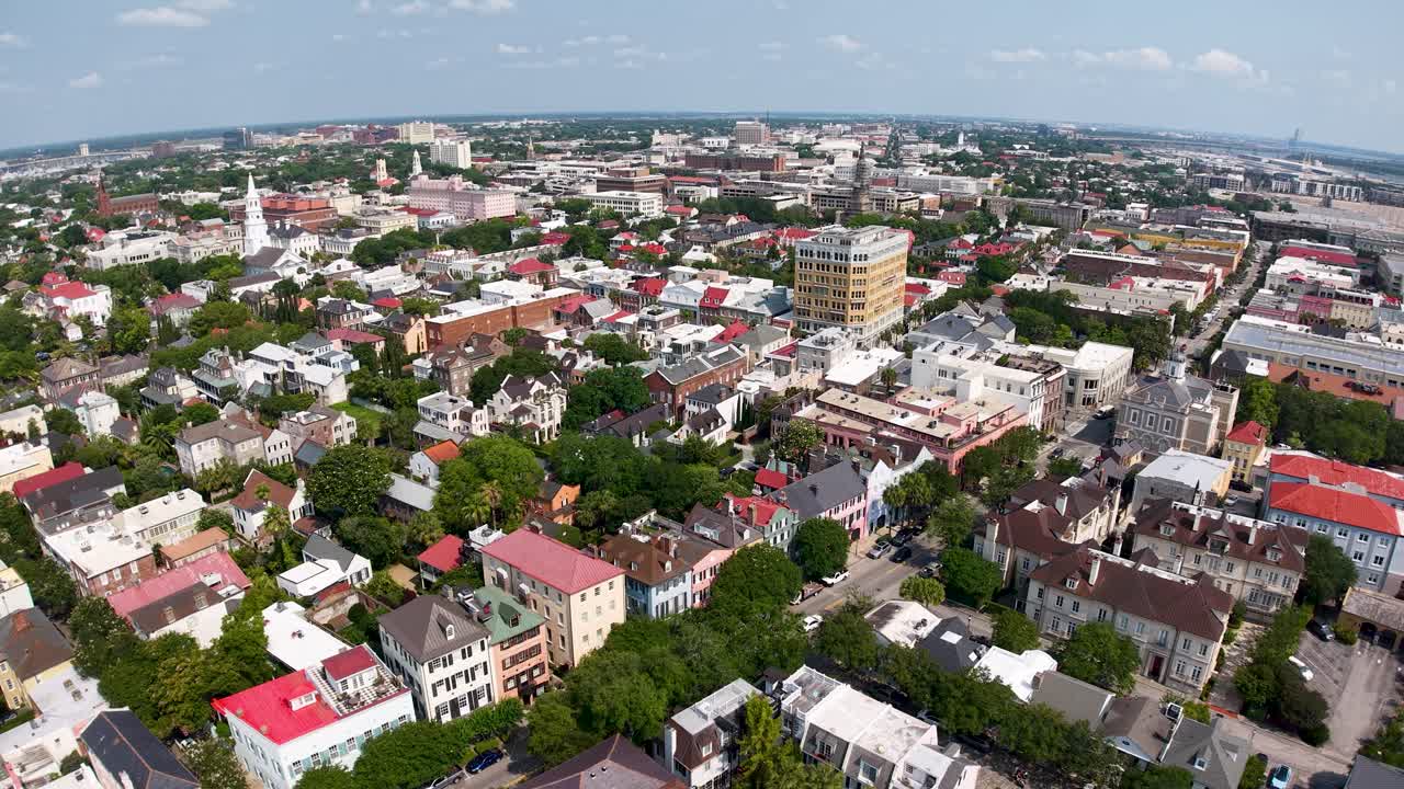 Drone footage shows a sweeping aerial view of downtown Charleston South Carolina highlighting historic buildings church steeples and tree lined streets