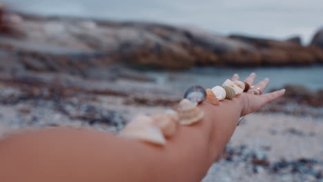 mujer de cerca equilibrando hermosas conchas marinas en el brazo disfrutando de las vacaciones de verano