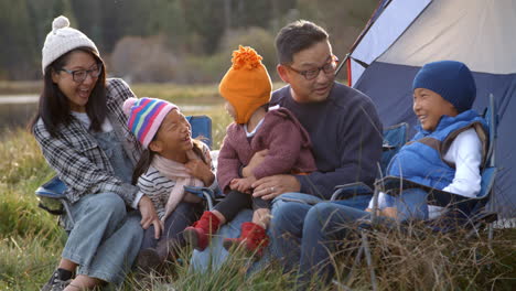 familia asiática en un viaje de acampada hablando fuera de su tienda