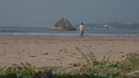 Sri-Lankan-Man-Walking-On-The-Sandy-Beach-Shore-In-Weligama,-Matara,-Sri-Lanka