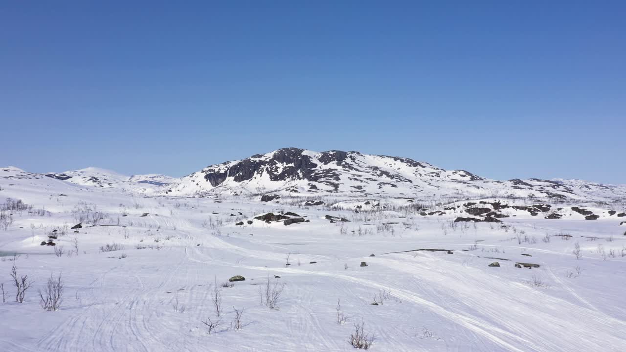 Flyfoto av snødekt fjell i et stort fjellandskap.