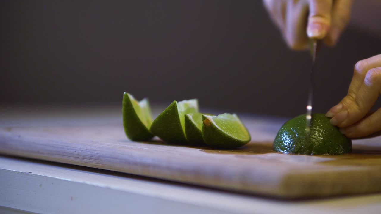 woman's hand cuts lime into slices on a cutting board