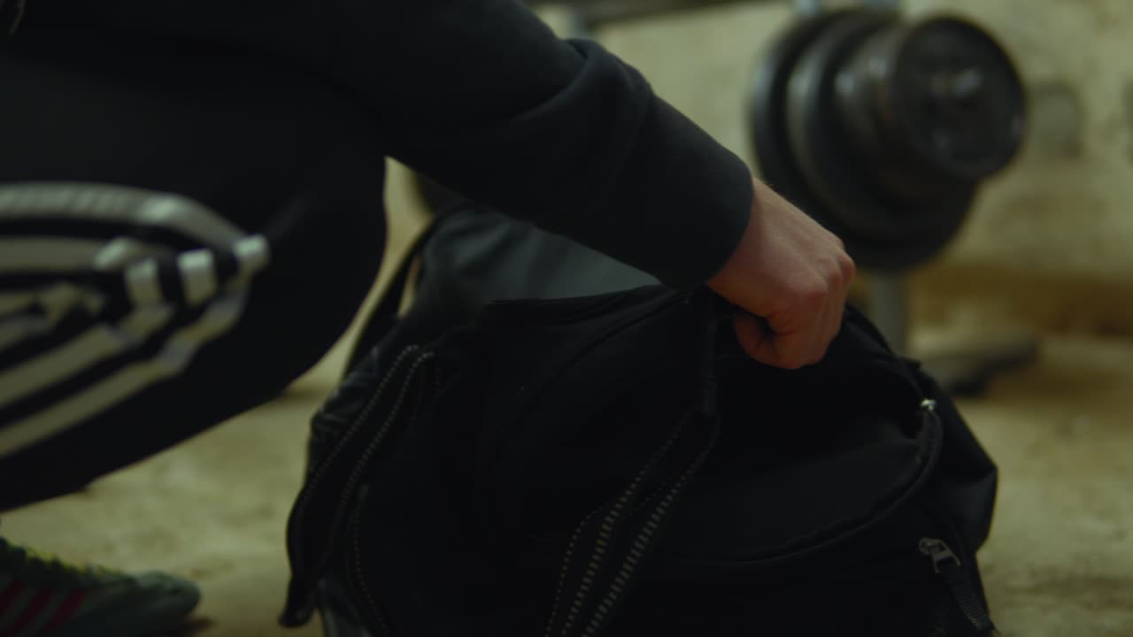 운동선수 의 손 이 체육관 에서 권투 장갑 을 꺼내기 위해 가방 에 손을 는다