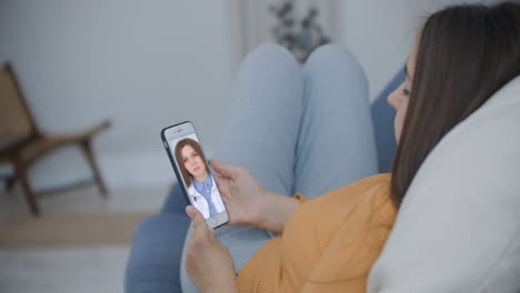 médico o terapeuta ayudan a aliviar el estrés de la crisis de coronavirus videoconferencia llamada en línea conversación en vivo de forma remota con la mujer sentarse en el sofá en casa usando una consulta médica de teléfono inteligente.
