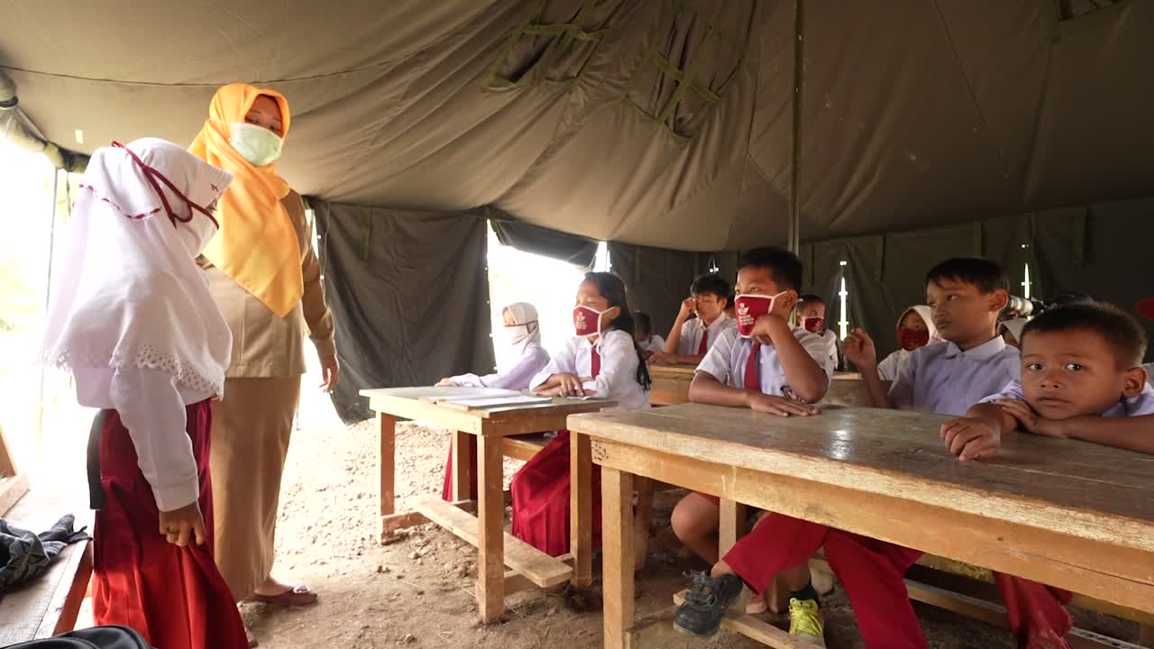 Students and a teacher in a temporary tent classroom