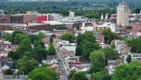 aerial wide shot of downtown with historic buildings and towers in lancaster, pa. green trees along row of house in american town.