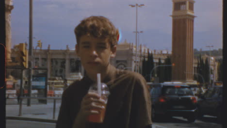 a young man drinks from a plastic cup on a city street