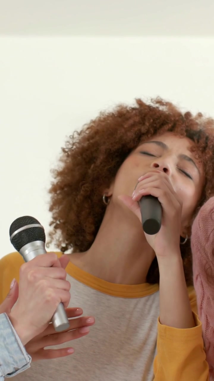 Vertical video: Opening frame on singer with mic, singing lead at home, dueting with denim jacket