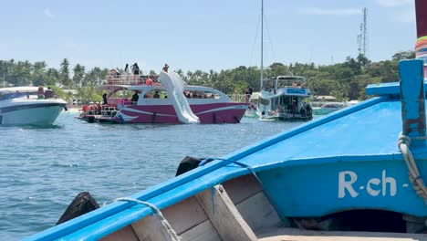a vibrant yacht with a slide hosts a lively gathering in sunny phuket, surrounded by clear blue waters and lush greenery