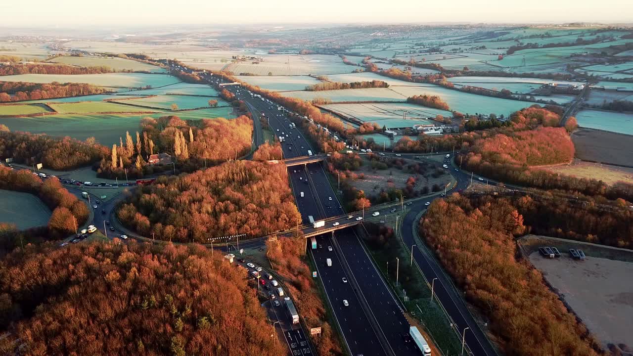Static Wide Drone Aerial View Of A Busy Motorway Junction With Cars And Trucks In The Winter With Orange And Brown Trees