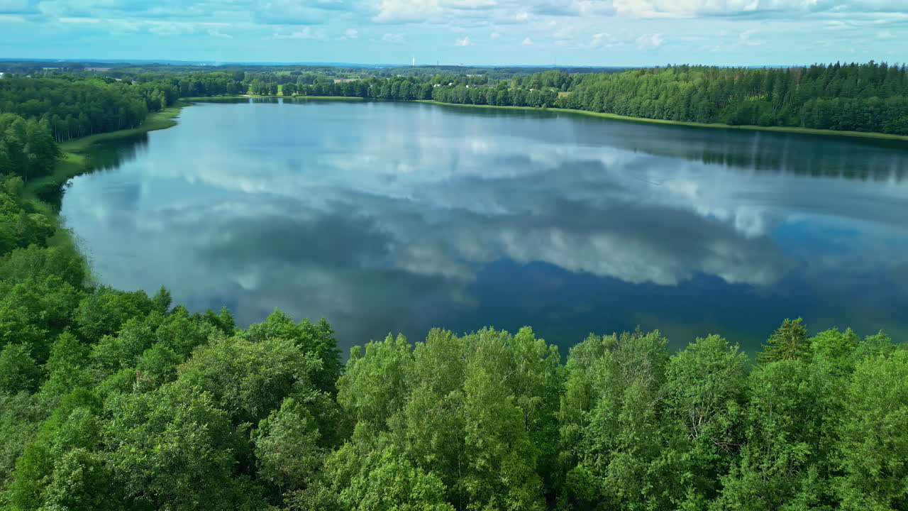 Clear Water Of A Lake With Mirror Reflections Surrounded By Dense Trees