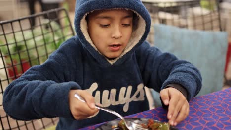 isolated-boy-eating-at-home-with-fork-from-flat-angle