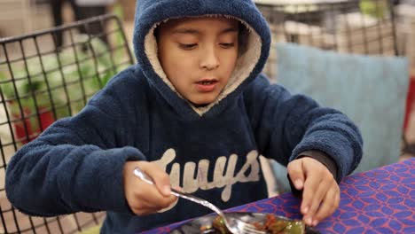 isolated boy eating at home with fork from flat angle