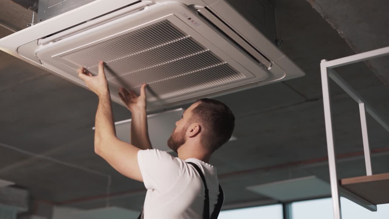 Portrait of an adult man in work uniform folding his hands to install an industrial air conditioner