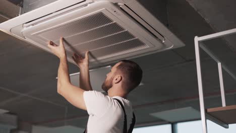 Portrait-of-an-adult-man-in-work-uniform-folding-his-hands-to-install-an-industrial-air-conditioner