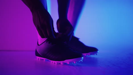 close up of black african male soccer player tying shoelace on studio slow motion. footballer tying his shoe. low section. tying football boots preparing for a football soccer match