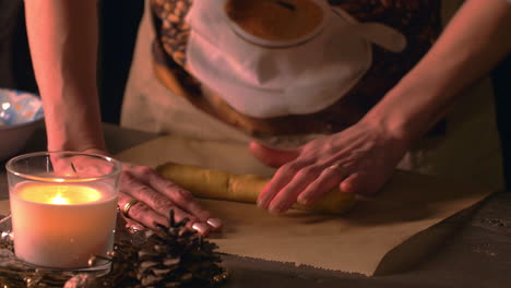 close up, woman roll out dough with bare hand. christmas decor ambient lighting