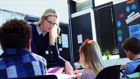 Teacher-helping-schoolgirl-with-her-homework-in-classroom