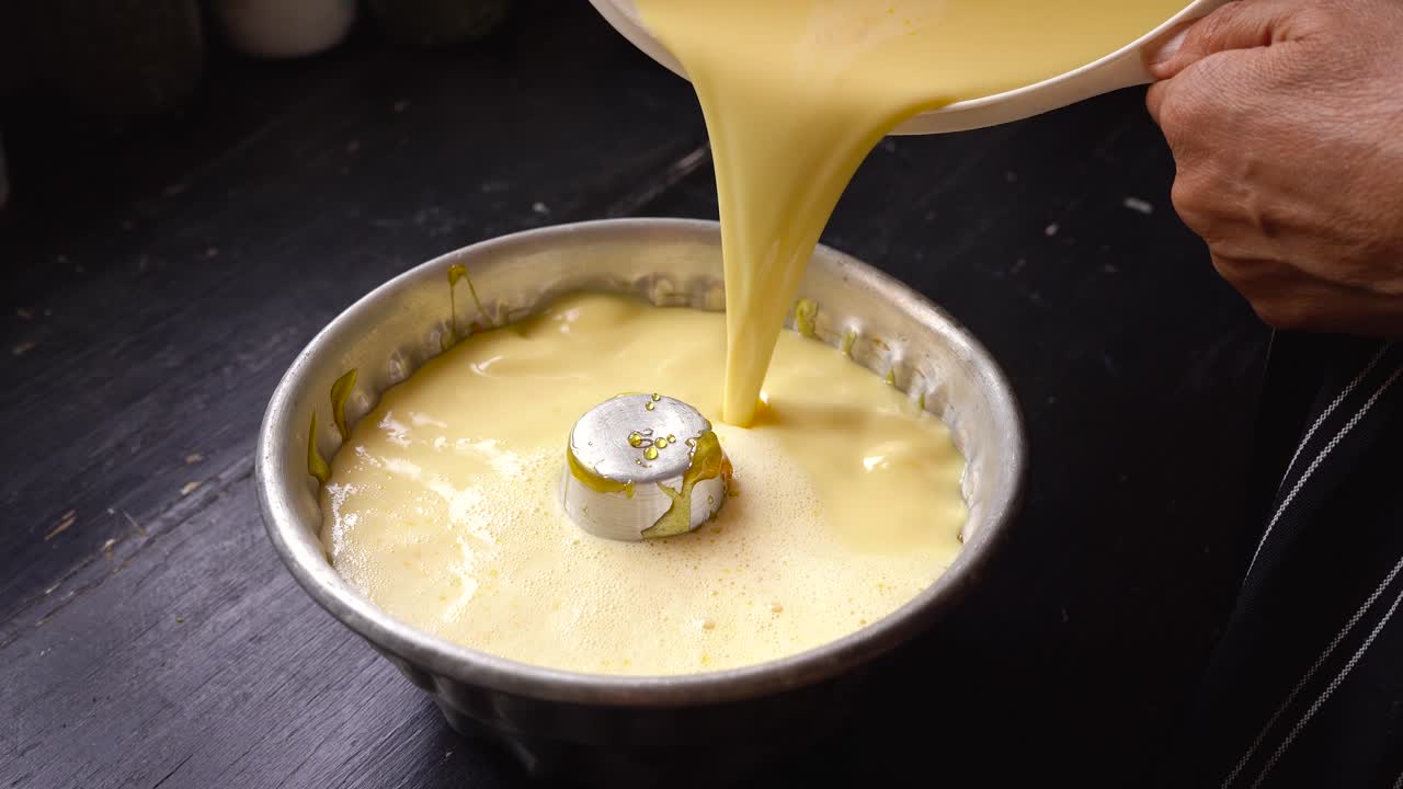 Baker pouring cake mixture into savarin mould, homemade flan