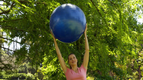 Mujer-En-Forma-Levantando-Una-Pelota-De-Ejercicio-En-El-Parque.