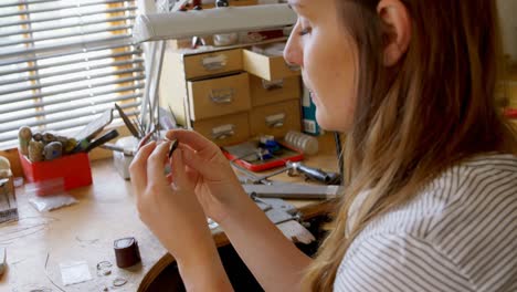 Diseñadora-De-Joyas-Femenina-Examinando-El-Anillo-En-El-Taller-4k